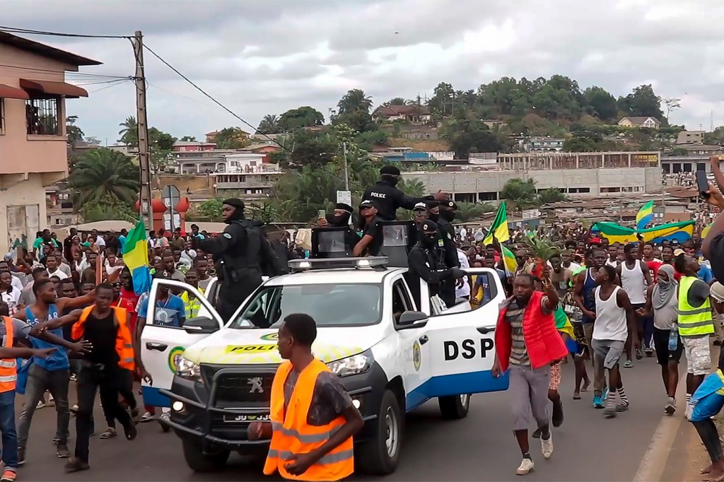 coup supporters walking around a white truck in Gabon