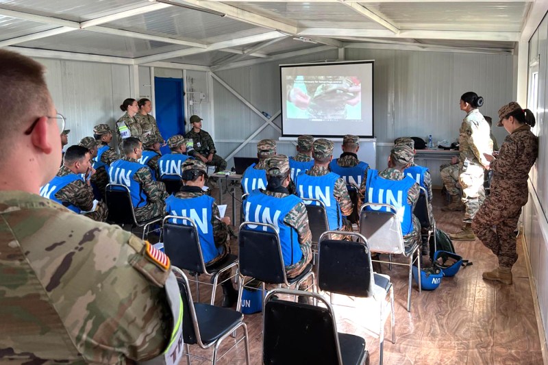 Army Reserve members wearing blue UN vests watching a video