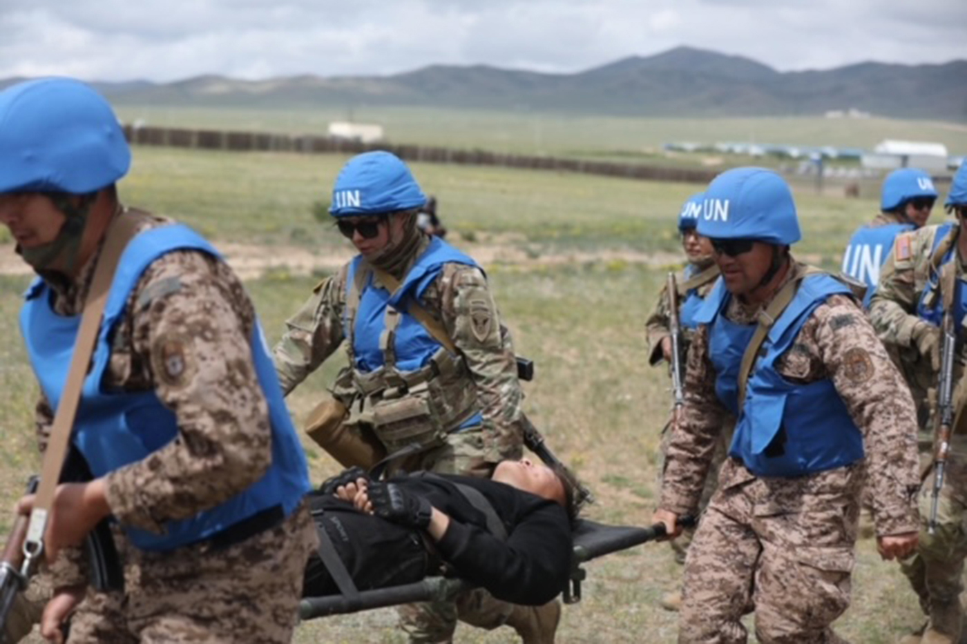 members of the Army Reserve carrying an injured person across a field in Mongolia