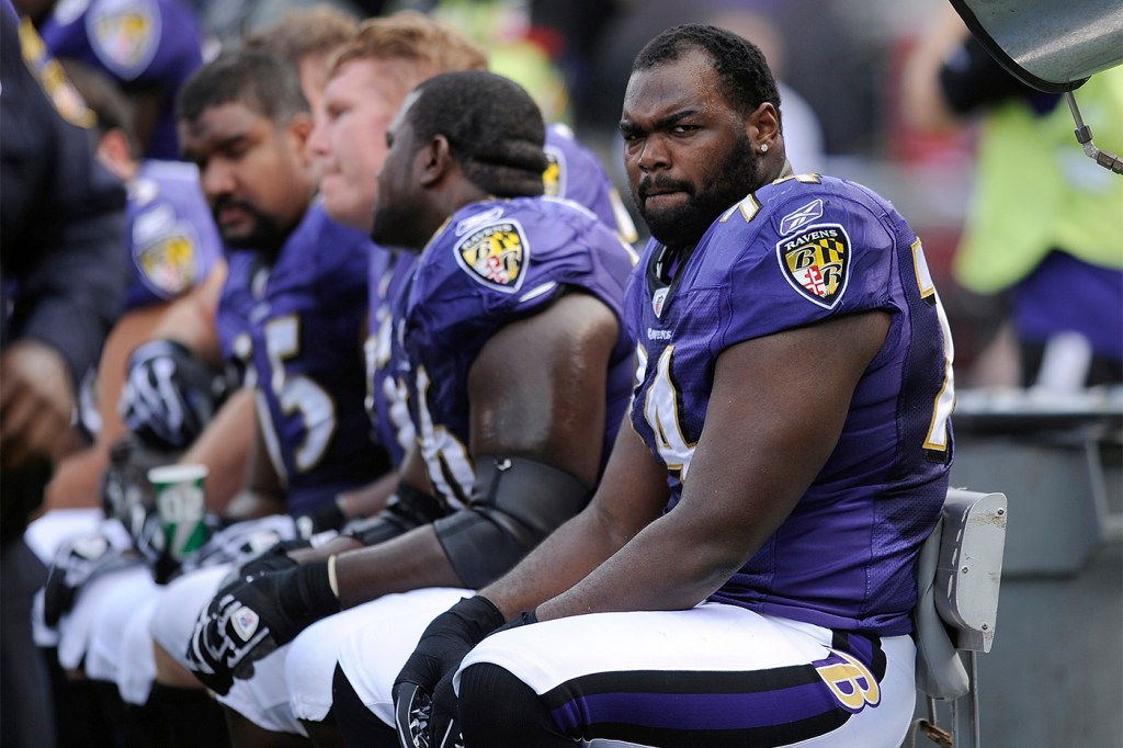 Michael Oher in Baltimore Ravens football gear sitting on the bench