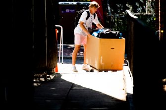 student pushing a move-in bin off campus