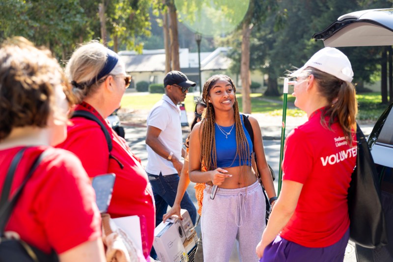 student talking with move-in volunteers on Oakland Campus
