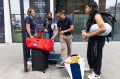 Students standing on a sidewalk in London with suitcases.