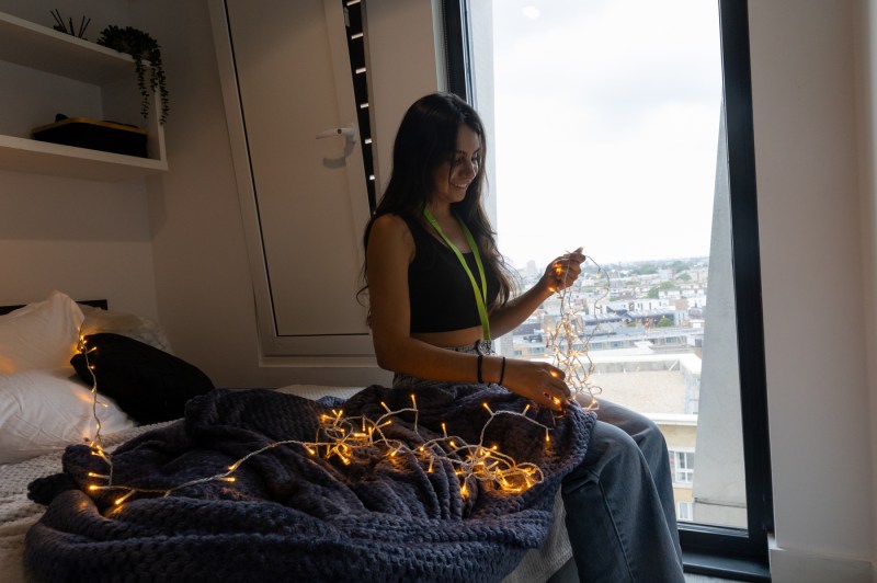 A student hangs up lights after moving into Northeastern's London campus.