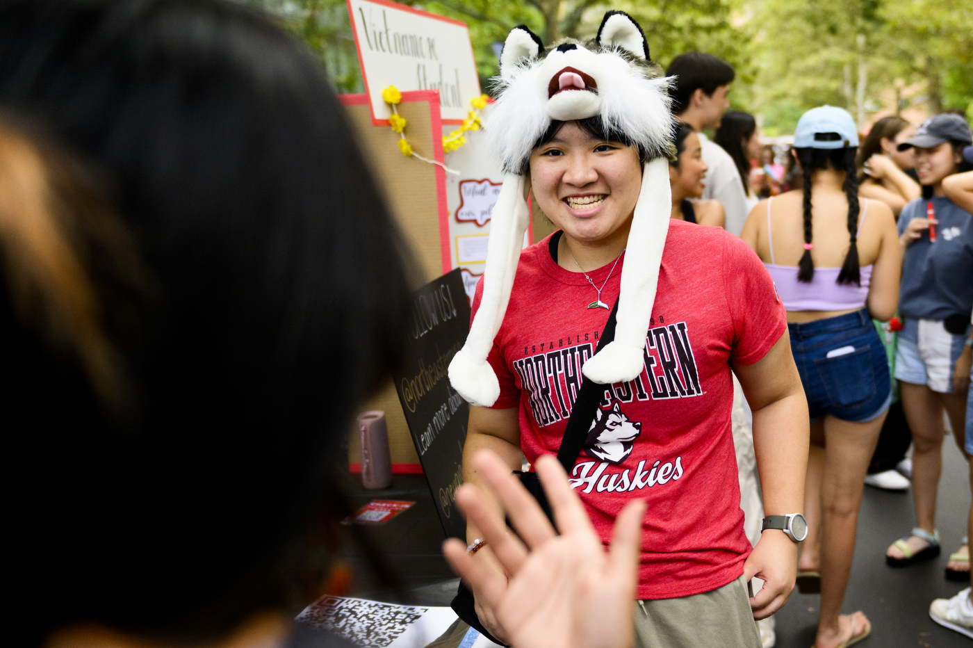 A person wearing a husky-themed hat talks to another person at Fall Fest.