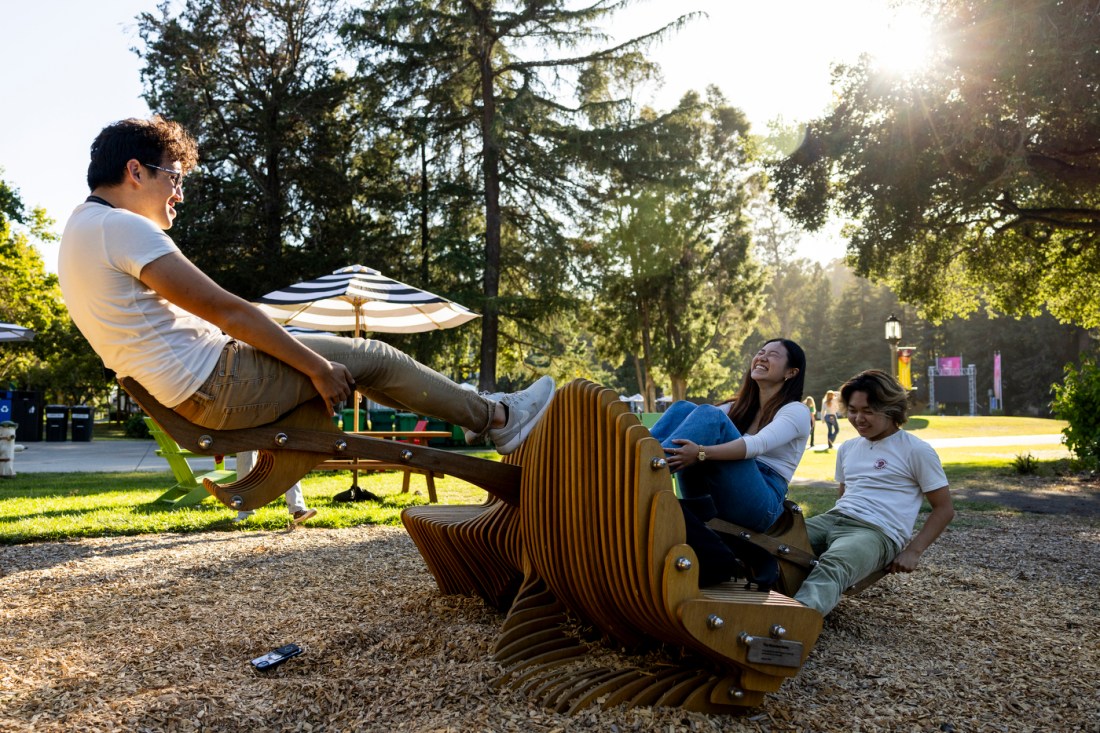 Three students using a wooden seesaw on Mills College campus. 