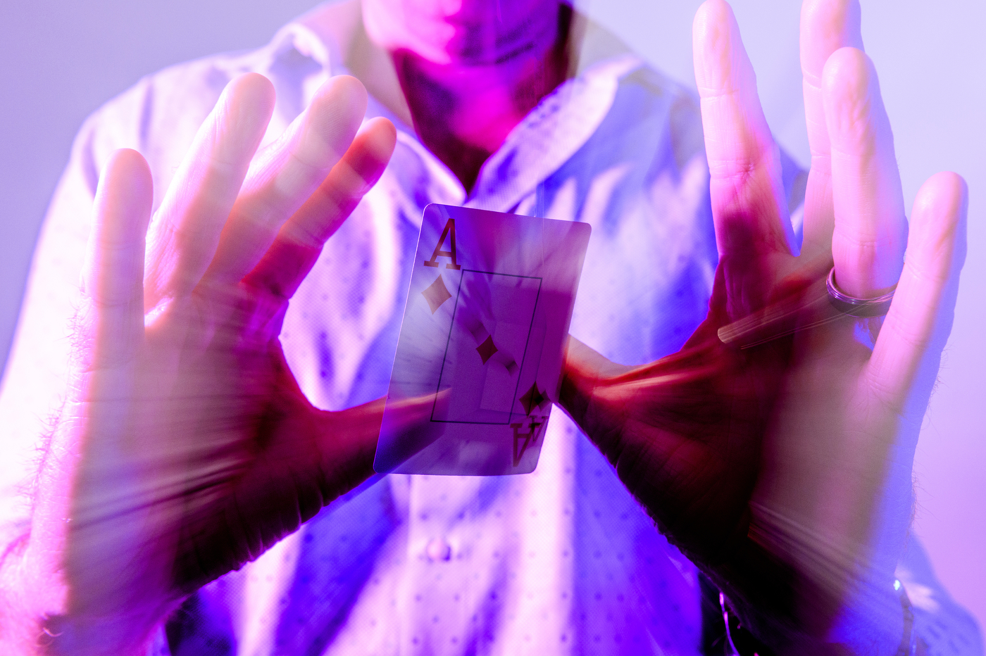 Person performing card trick with purple overlay on the photo.