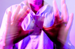 Person performing card trick with purple overlay on the photo.