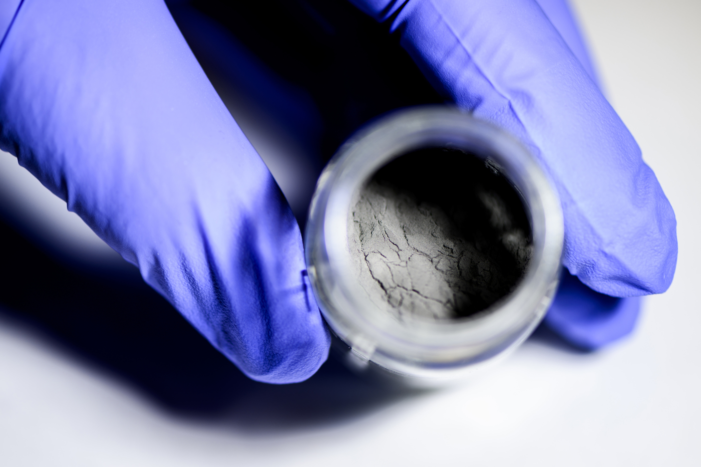 A hand holds iron powder, the next carbon-free energy, in a container. 
