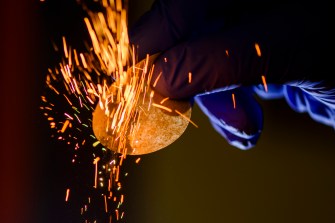A glove holds a device as sparks fly across the room.