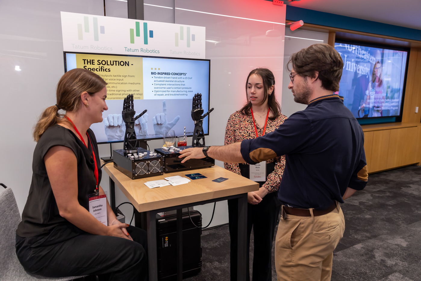 Three people interacting with models from Tatum Robotics at the Experience Powered by Northeastern campaign stop in Arlington.