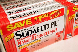 An orange and white box of Sudafed PE nasal decongestant.