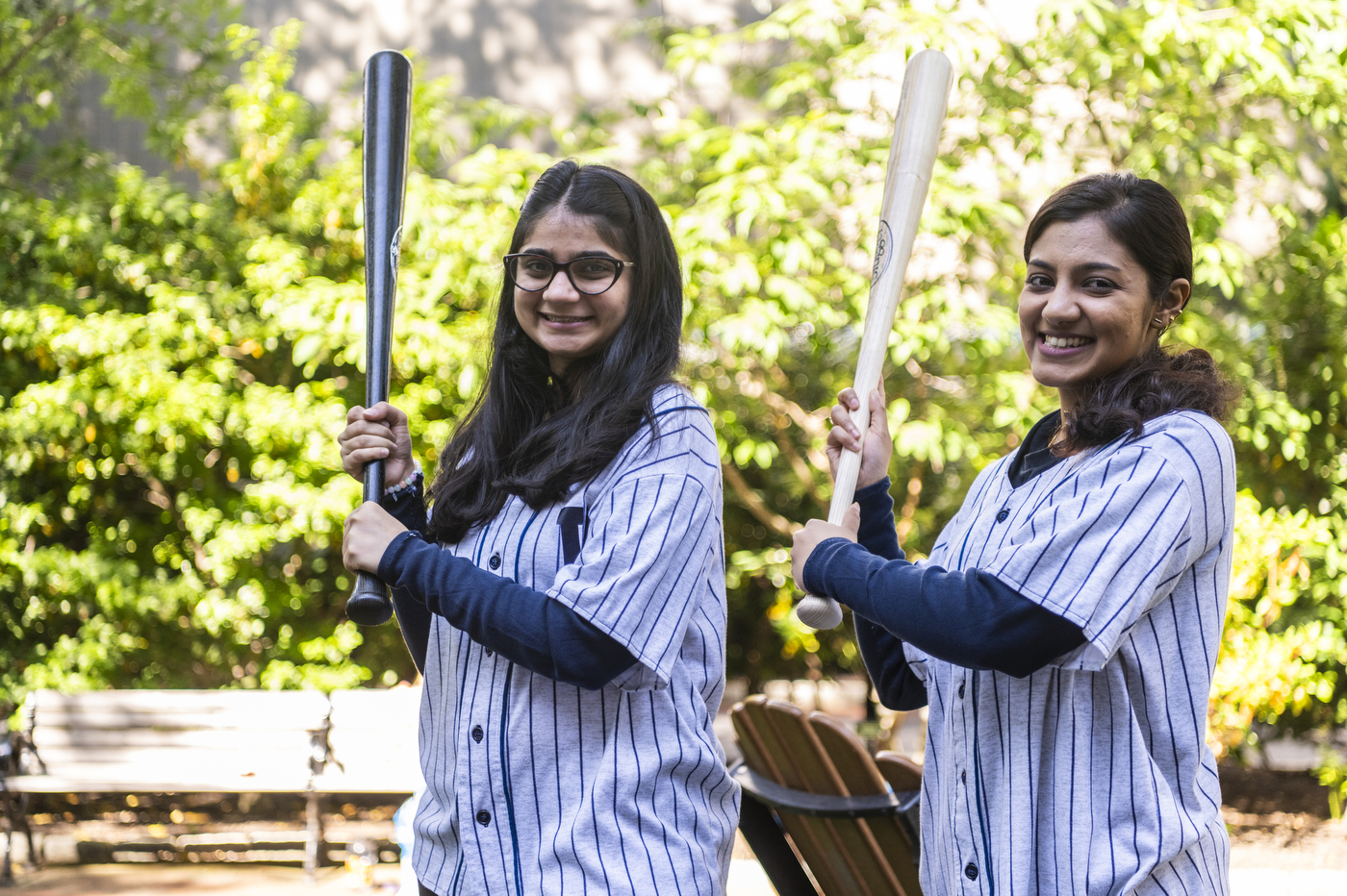 Students holding baseball bats and smiling