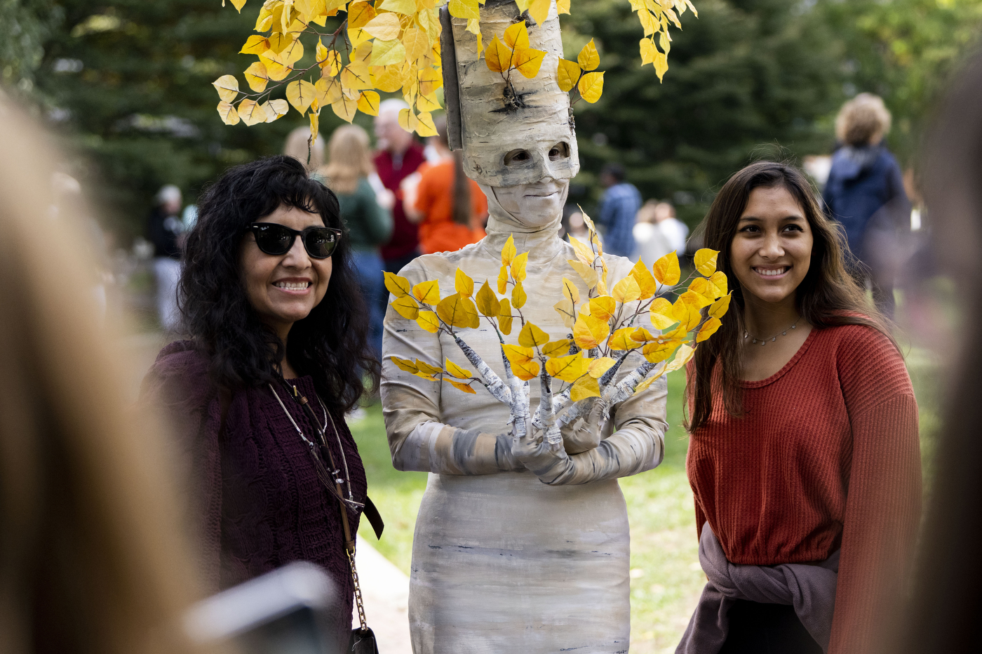 People posing with someone dressed as a birch tree.