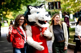Family posing with Paws mascot at Family and Friends weekend.