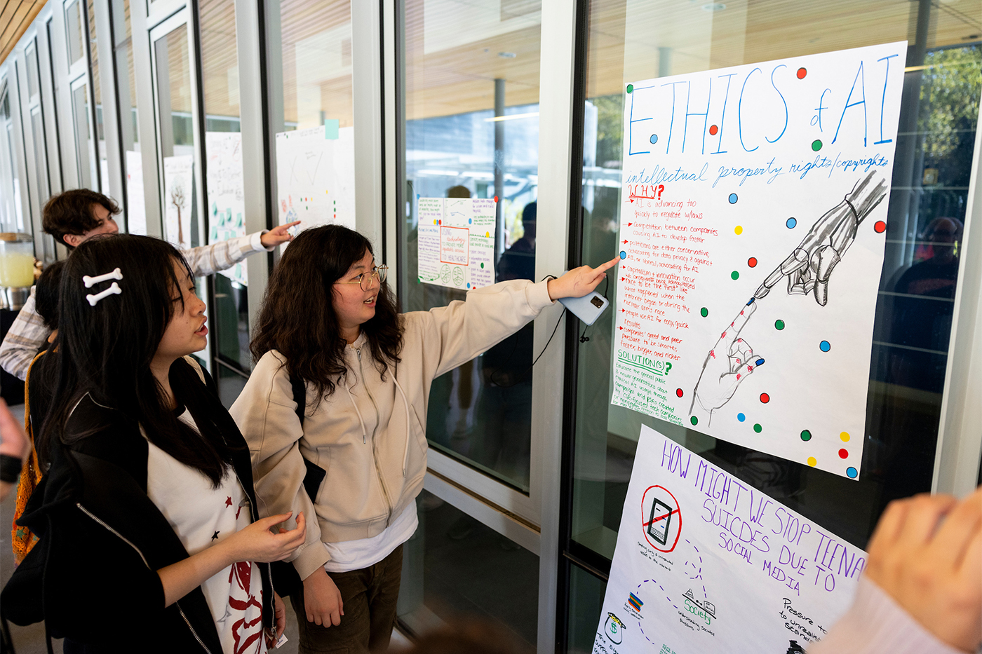 Students pointing to a posterboard abotu the Ethics of AI.