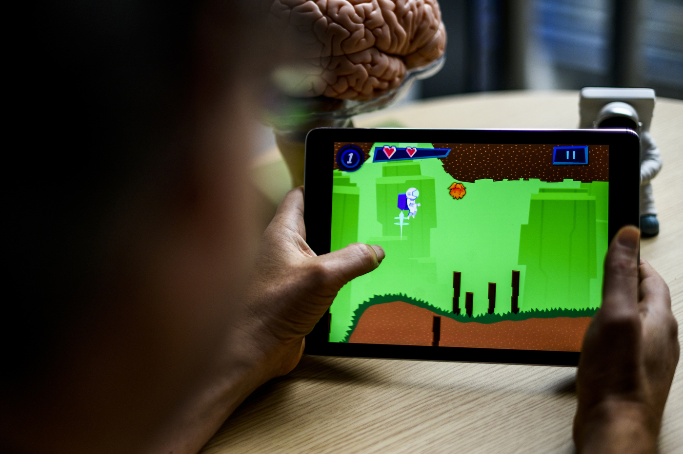Person using an iPad to play a 'brain training' game that involves flying an astronaut around obstacles.