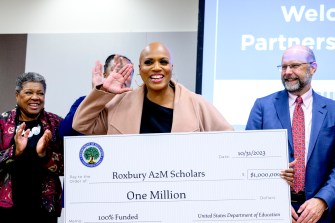 Roxbury Community College Interim President Jackie Jenkins-Scott, left, and Northeastern University Chancellor Ken Henderson, right, look on as U.S. Rep. Ayanna Pressley as she holds a large check for $1 million.