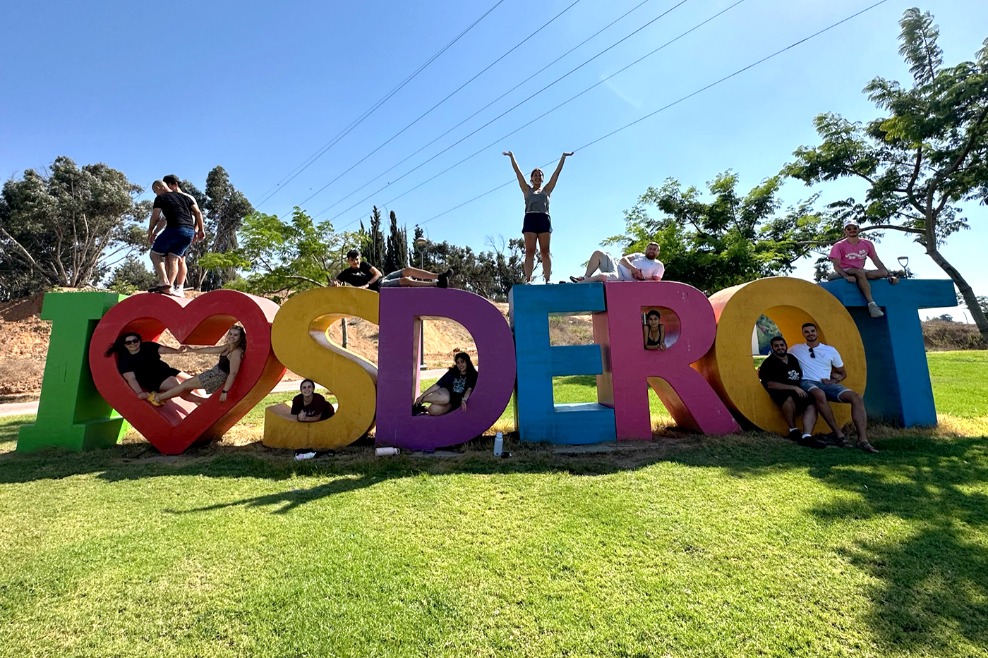 Students posing on giant letters that spell out I (heart symbol) SDEROT.