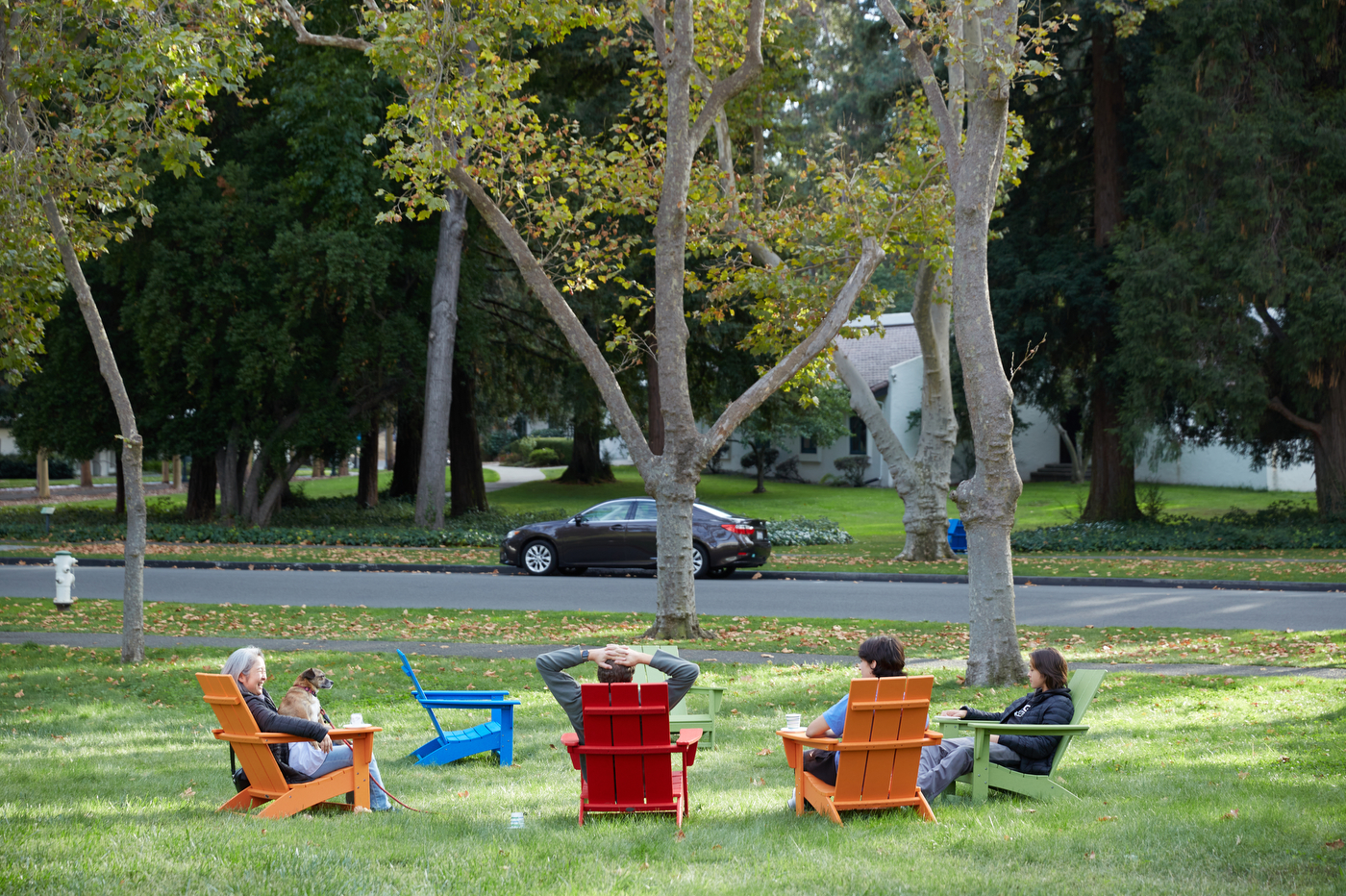 Students and families sitting in rainbow colored adirondack chairs.