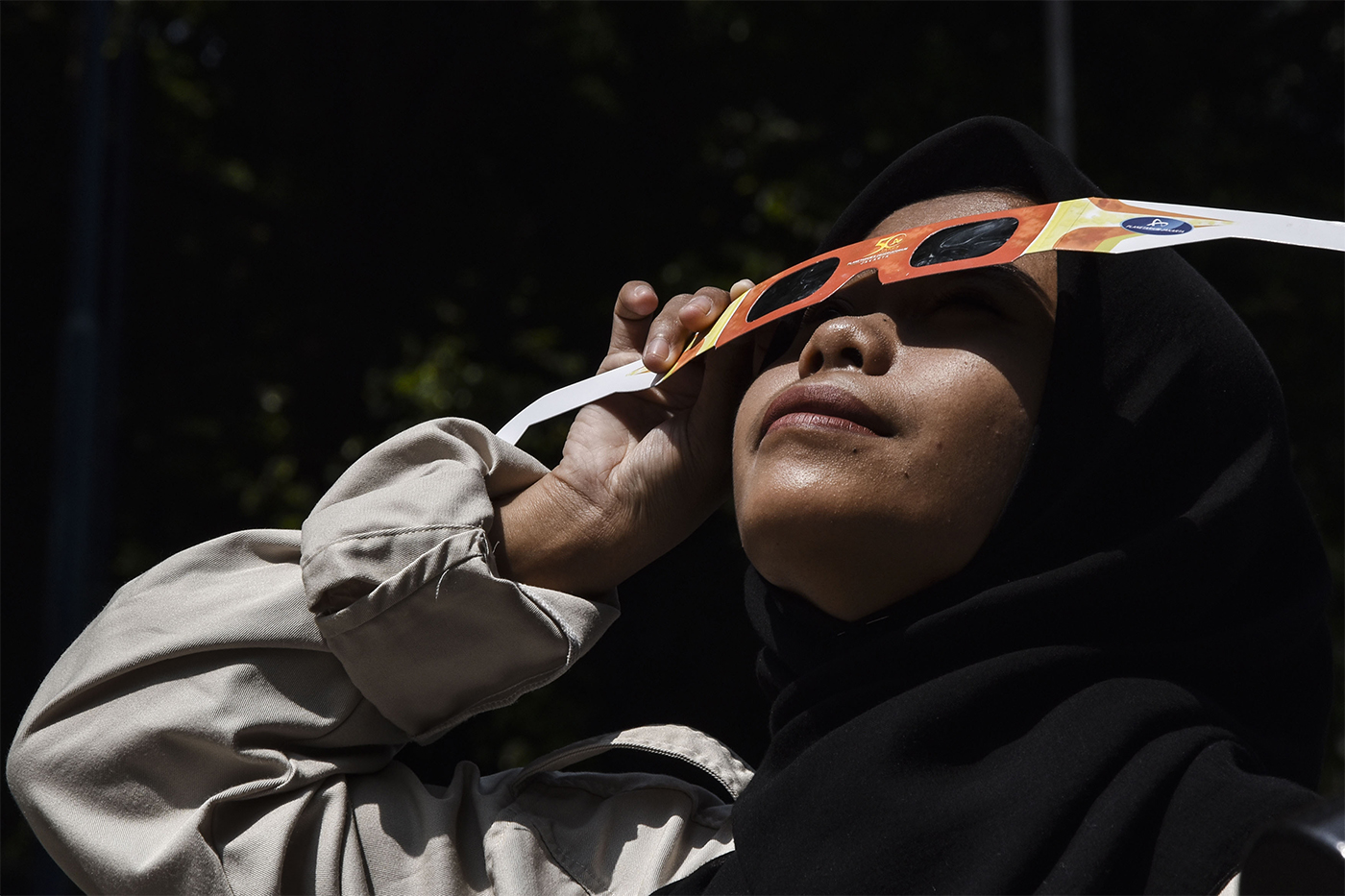 Student wearing solar eclipse glasses looking up at the sky.