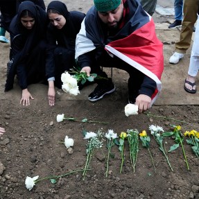Muslim community members placing flowers on a grave.