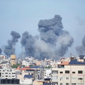 From a distance, smoke rises over buildings in the Gaza Strip into the sky
