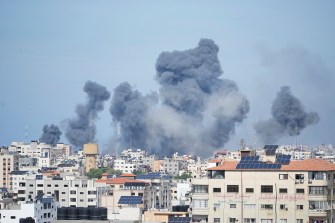 From a distance, smoke rises over buildings in the Gaza Strip into the sky