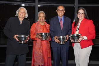Four people stand together, holding awards.