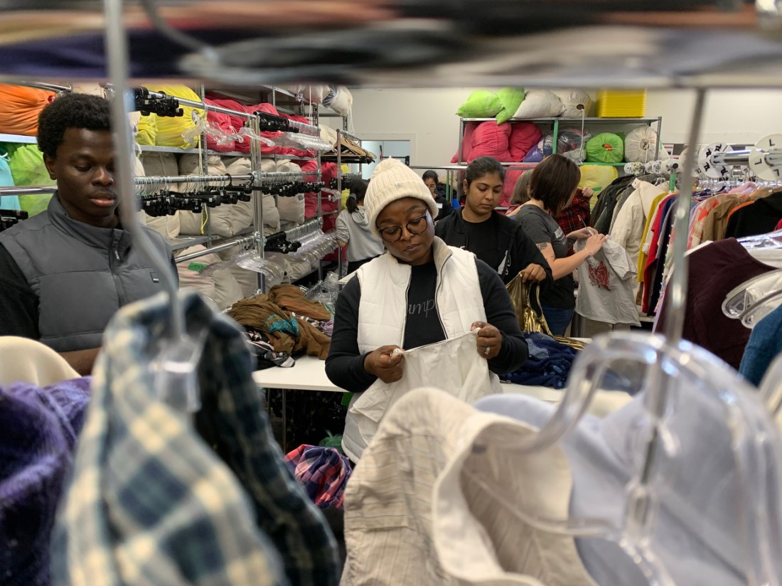 Students sorting through racks and piles of clothing.