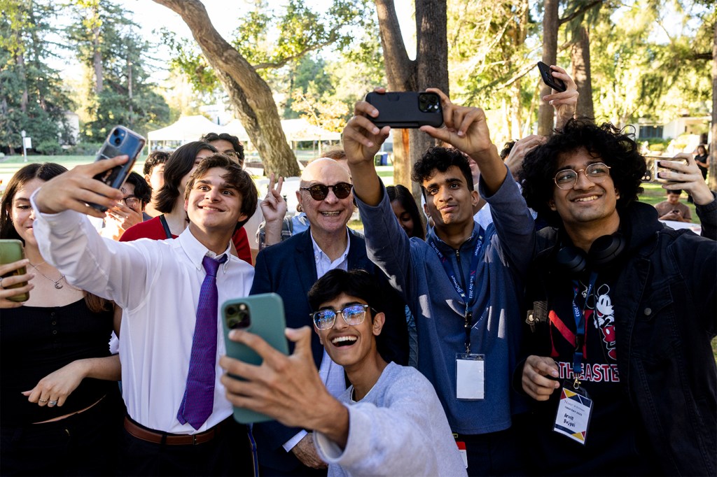 President Aoun posing for selfies with a group of students.