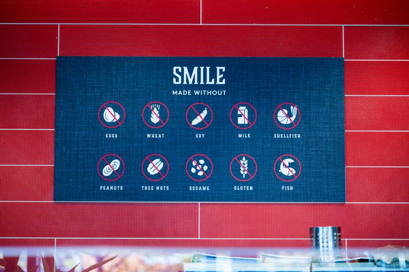 Banner in the United Table dining hall that says "Smile made without eggs, wheat, soy, milk, shellfish, peanuts, tree nuts, sesame, gluten, fish"
