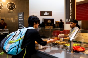 NU dining worker serving students food in the United Table dining hall.