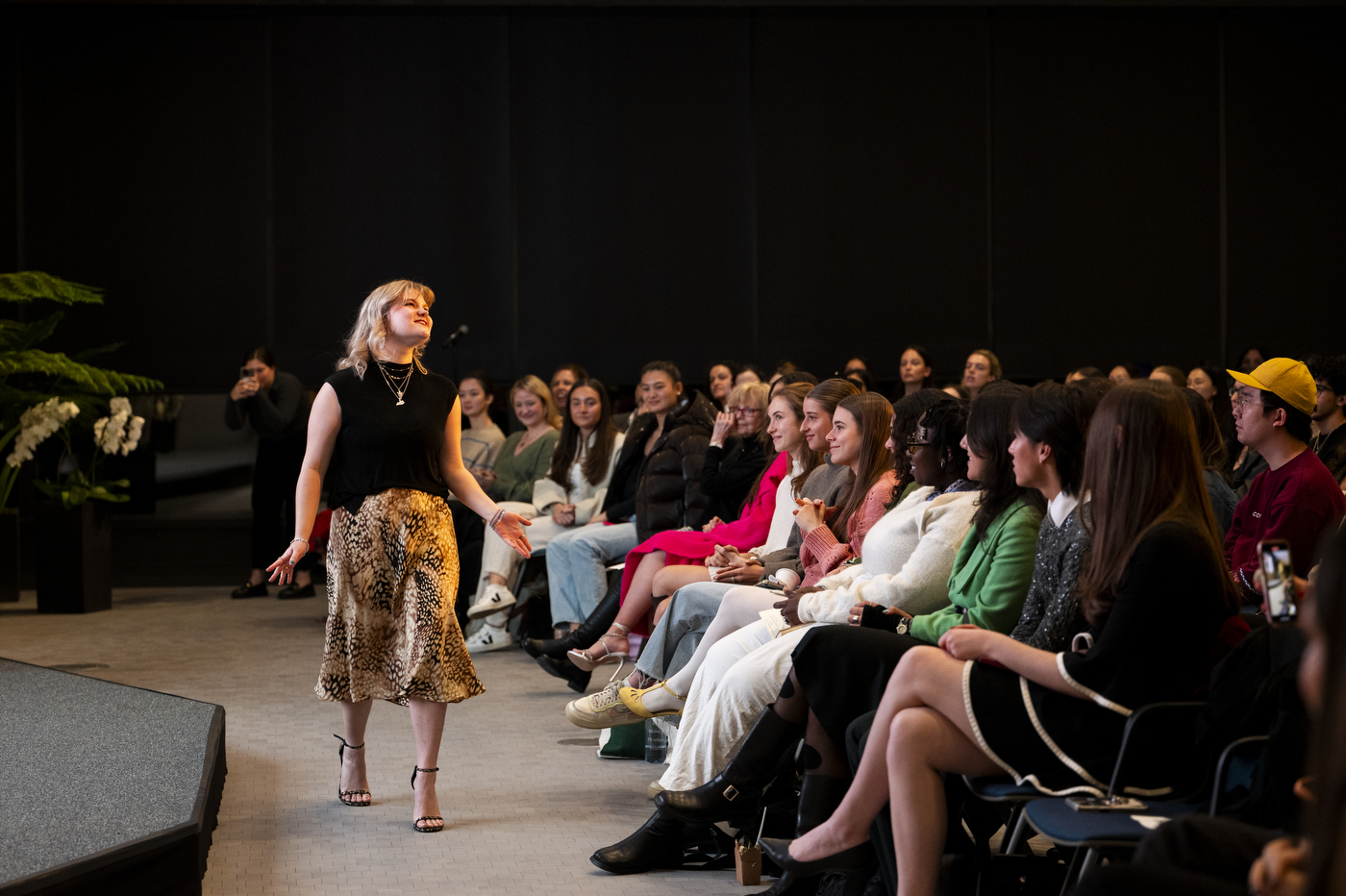 Student modeling a pair of Stuart Weitzman sparkling leopard print heels in front of the audience at the event.