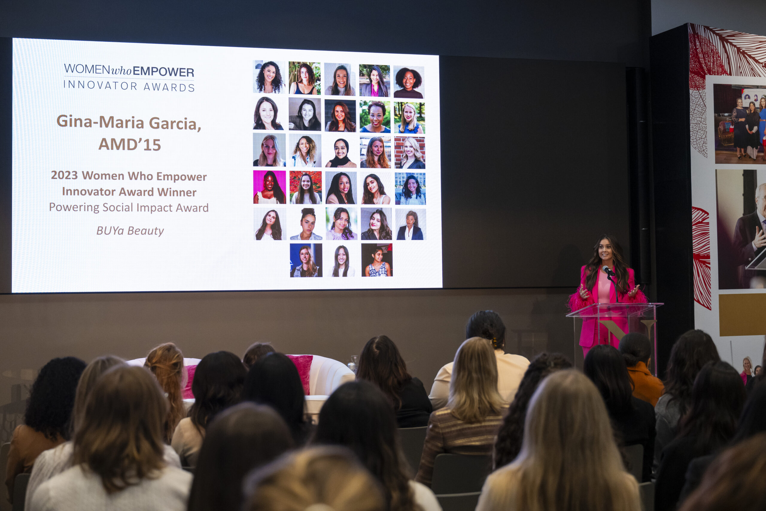 Gina-Maria Garcia speaking at a Women Who Empower summit in front of a screen displaying her name and information. 