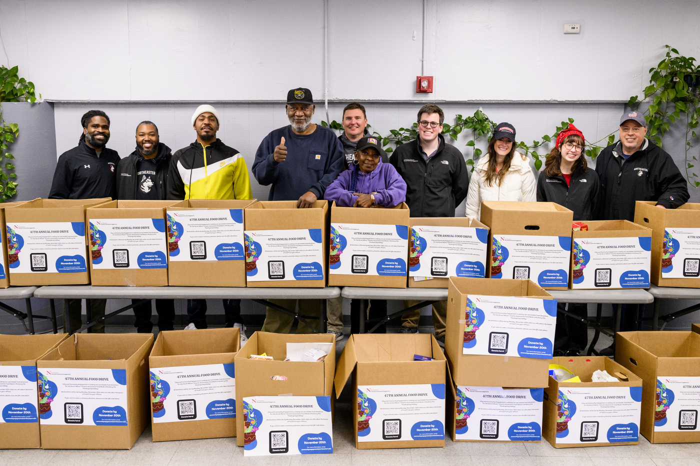 Members of the Northeastern community posing behind boxes of food donations. 