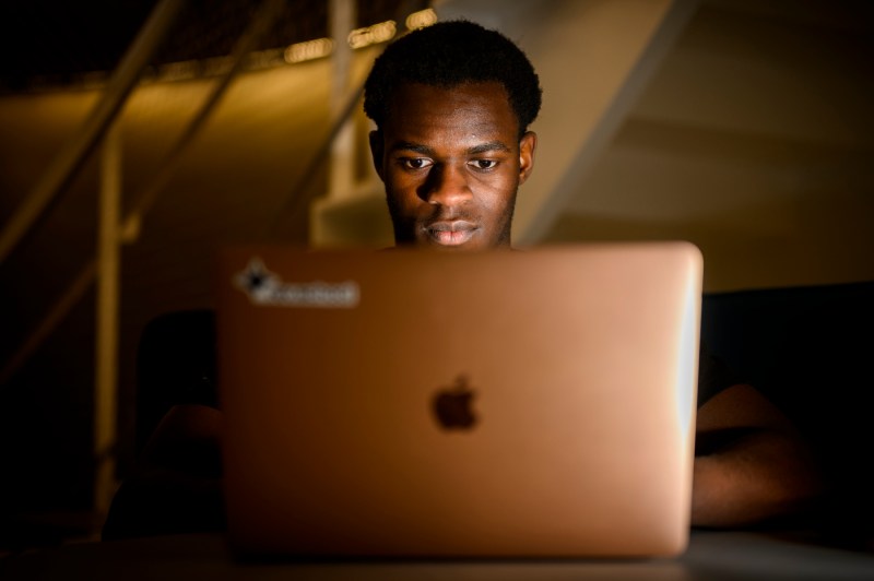 David Alade working on his Apple Macbook laptop. 