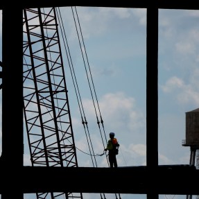 Silhouette of a worker on the framework of a battery plant.