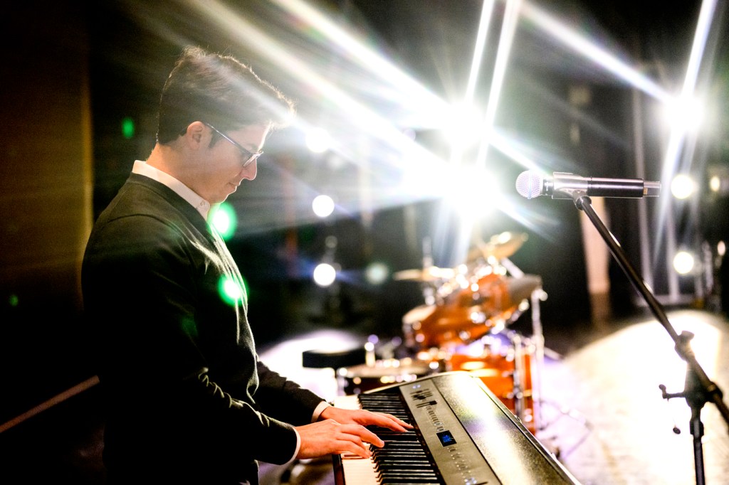 James Gutierrez plays the keyboard on stage with lights shining on him.