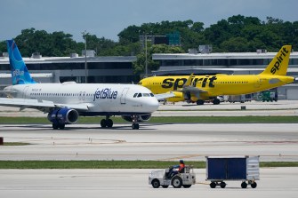 A JetBlue plane and a Spirit plane on different sections of a runway.