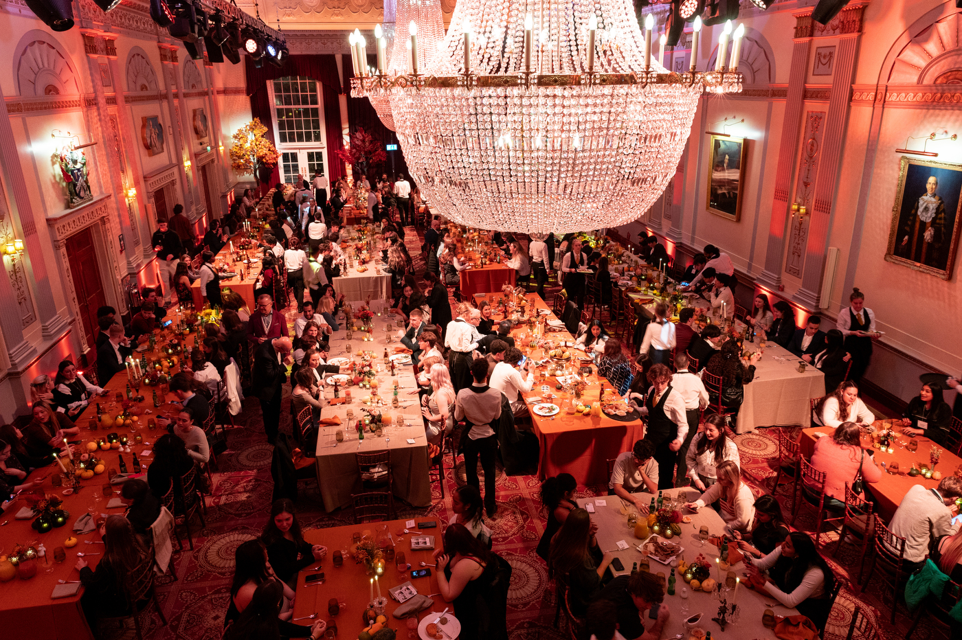 A large crowd sits together in a ballroom to celebrate Thanksgiving.