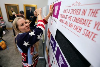 Molly Wheeler wearing a sweater with stars and stripes on it sets up an interactive board display.