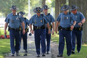 A group of six Massachusetts state police officers in uniform walking on a sidewalk.