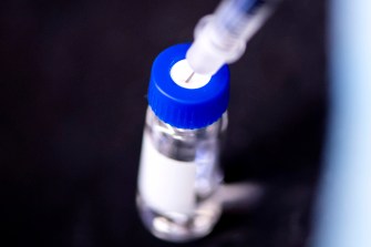 Syringe withdrawing vaccine from a vial.