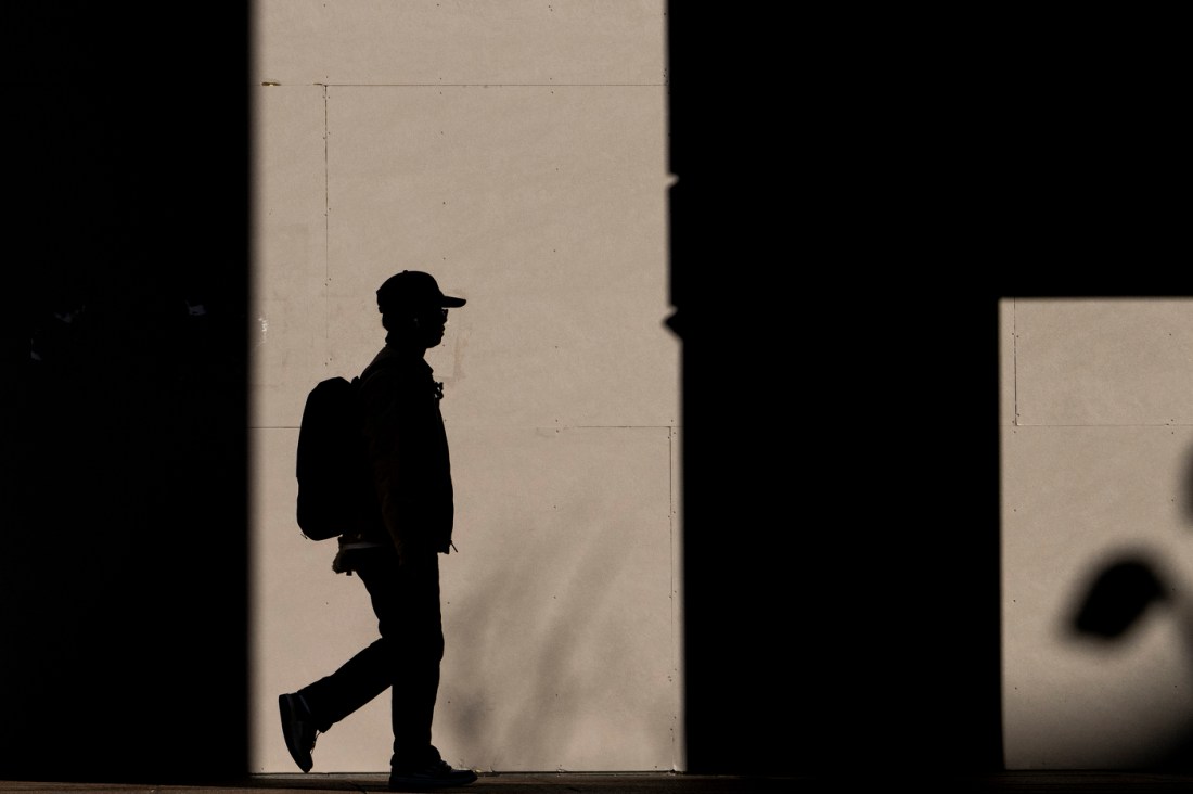 Silhouette of a Northeastern community member walking next to Snell Library. 