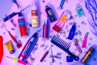 Curly hair care products on a white background photographed in purple lighting.