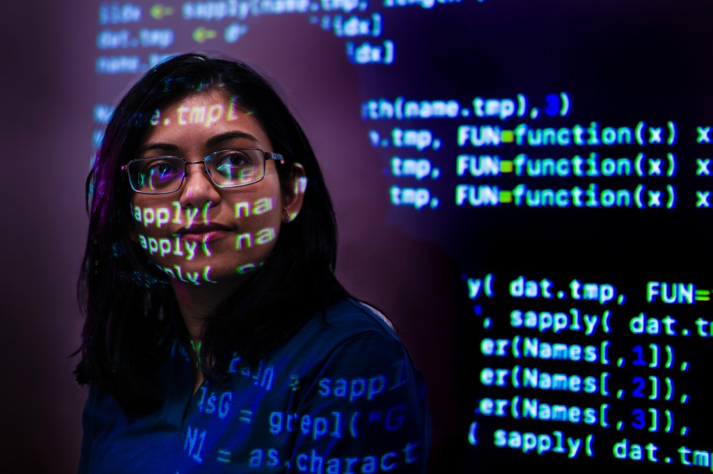 Headshot of Srirupa Chakraborty with lines of code projected on to her face.
