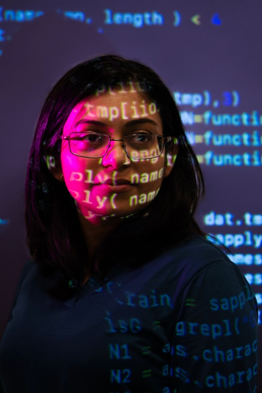 Headshot of Srirupa Chakraborty with code projections displayed on her face.