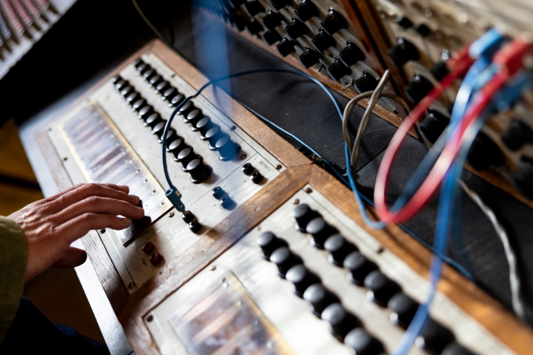 Person running their hand along the Buchla 100 Synthesizer.