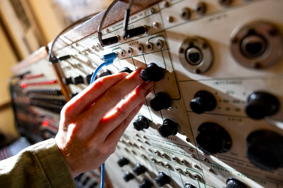 Person turning knobs on the Buchla 100 Synthesizer.